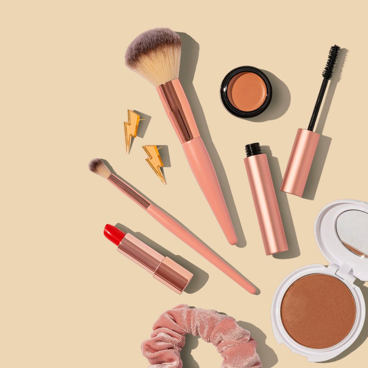 Makeup brushes, cosmetics and beauty accessories arranged on a light background.
