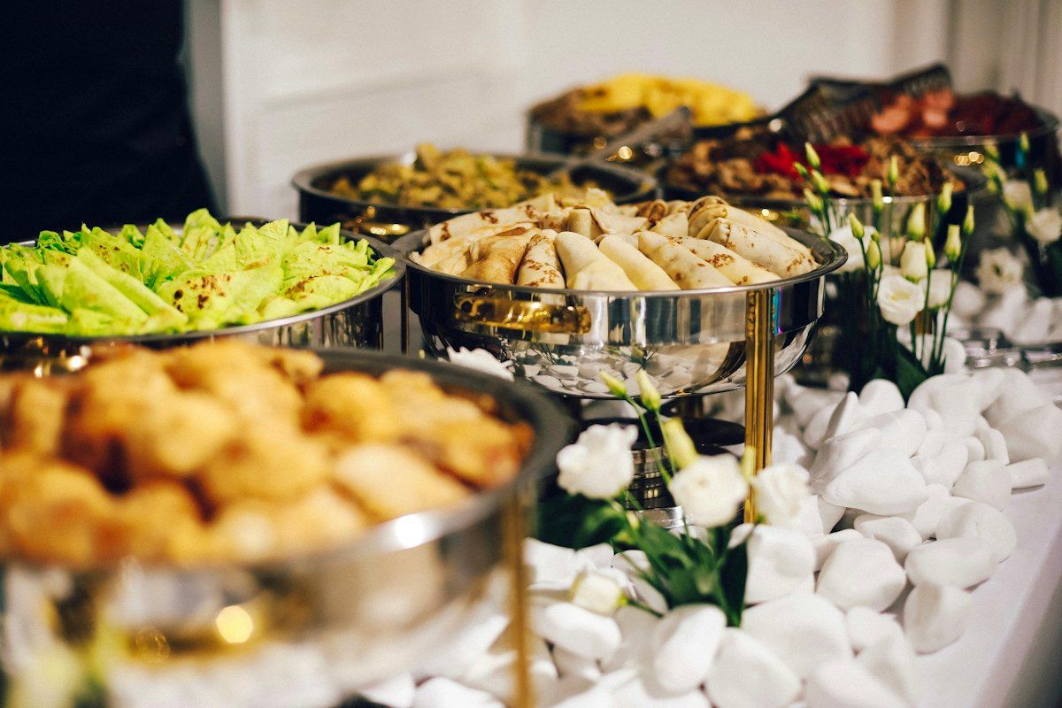 A carefully arranged buffet with food in metal serving dishes and table settings.